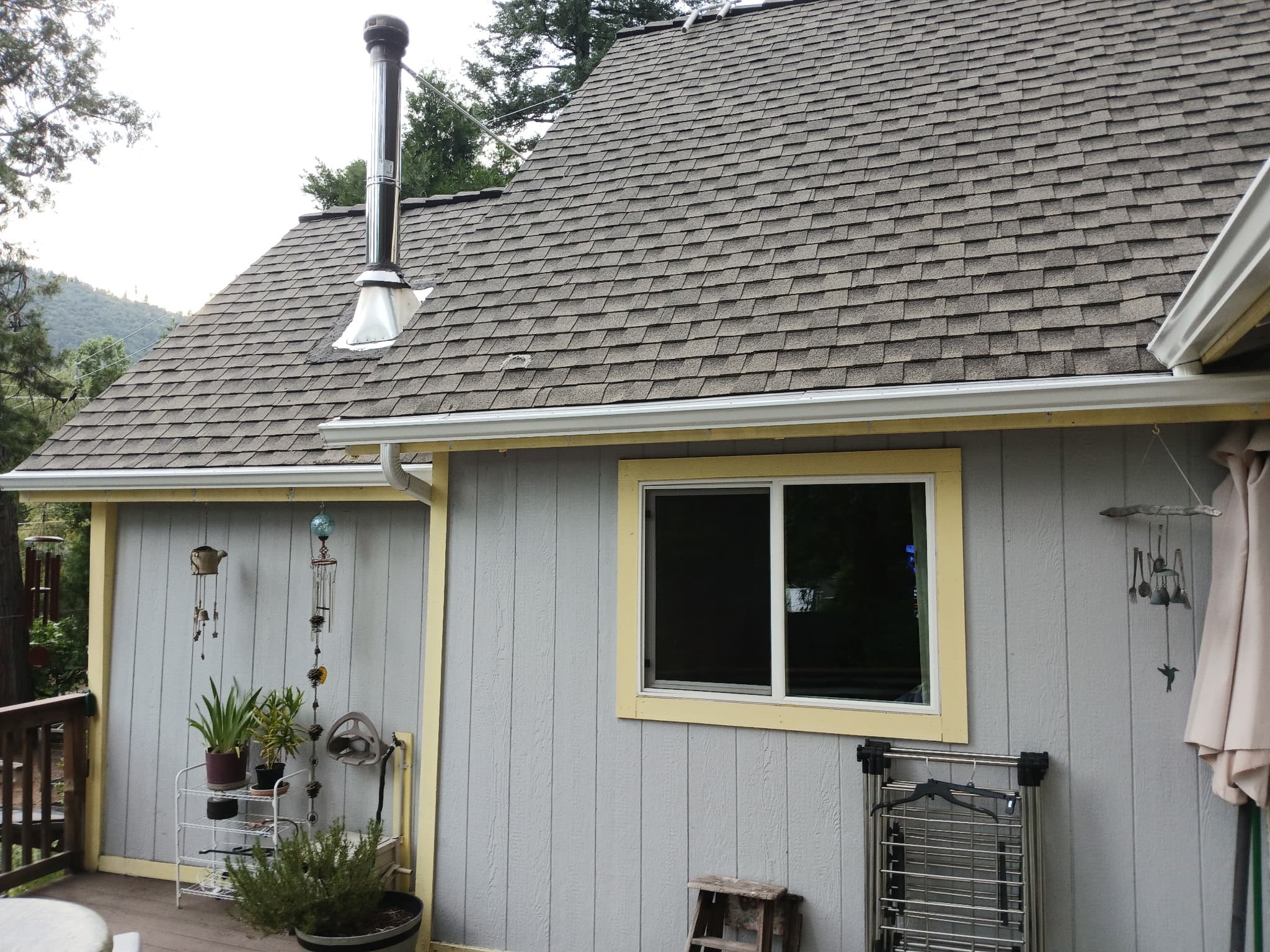 Gray mountain home with chimney pipe and brand-new gutter line in Weaverville