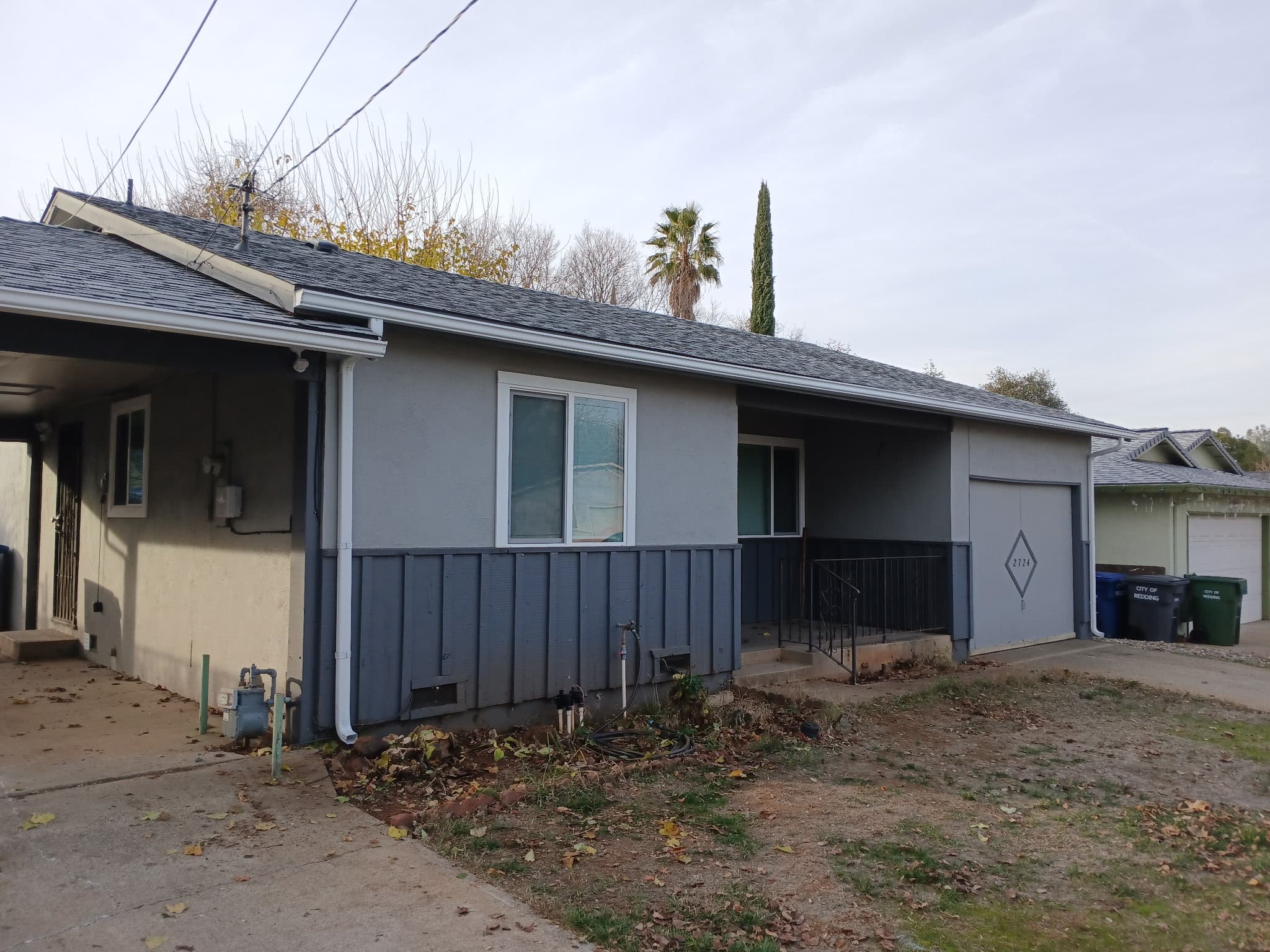 Gray board-and-batten ranch with fresh white gutters and downspouts in Anderson