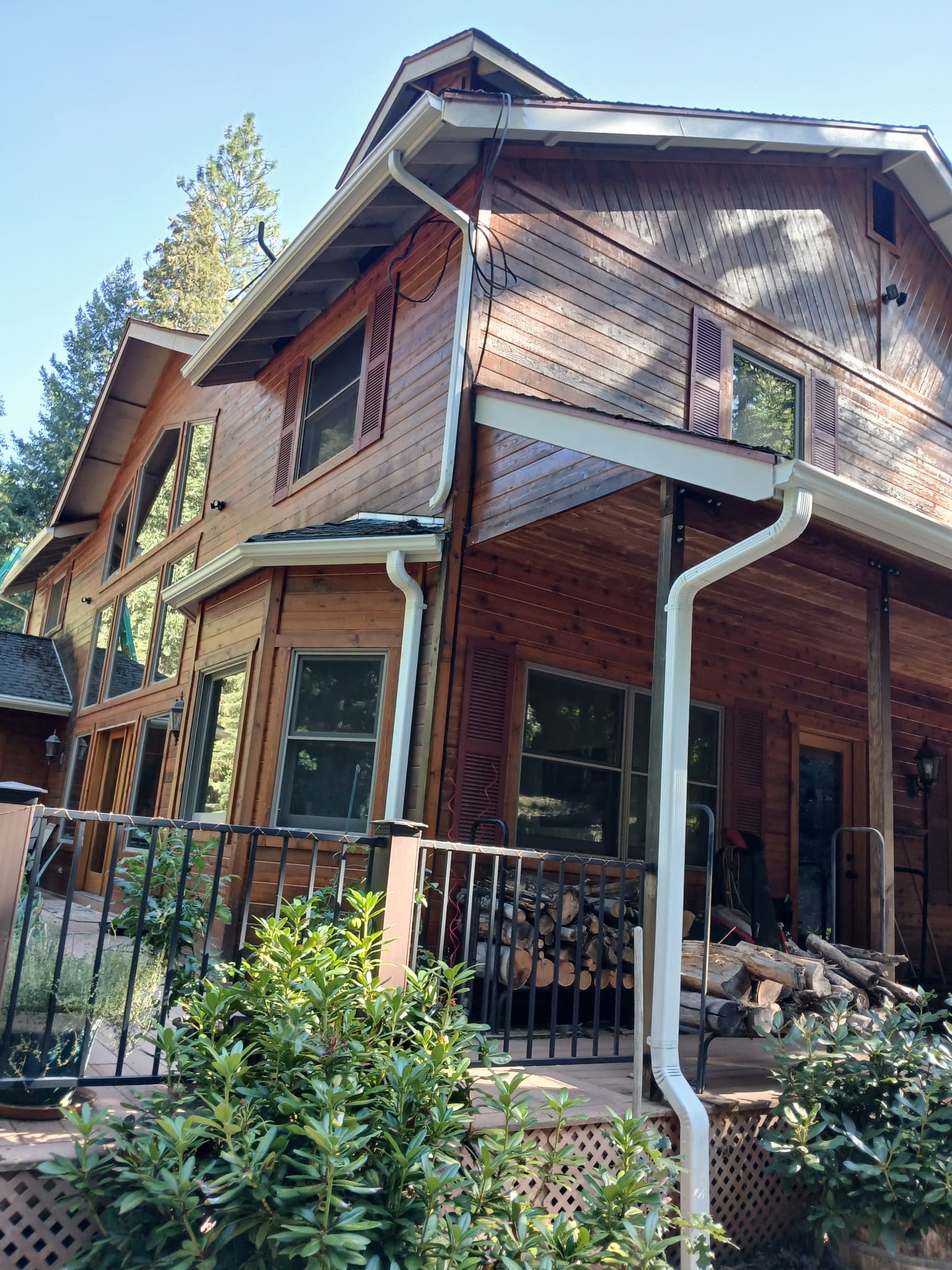 Multi-story cedar cabin with fresh white seamless gutters and downspouts in Whitmore